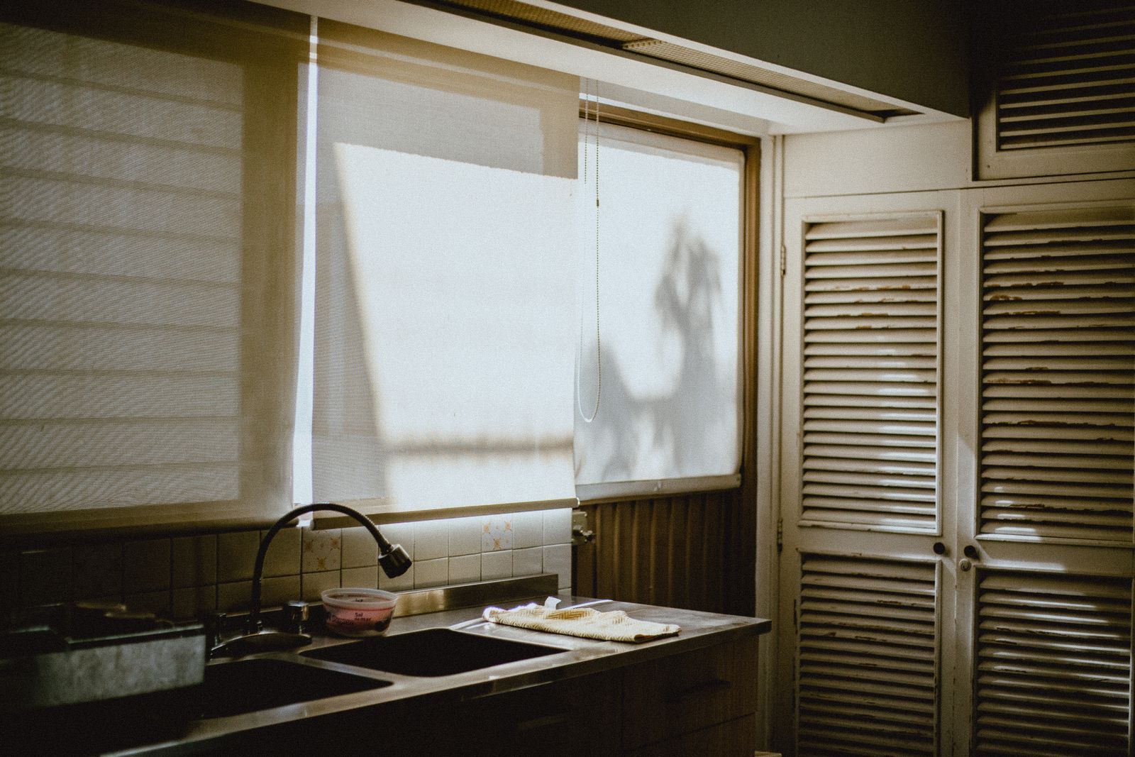 Cloth-wrapped kitchen tongs cleaning blinds